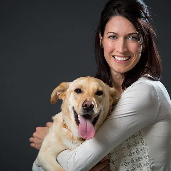 Ashley Spencer head shot, while she is holding a golden retreiver dog