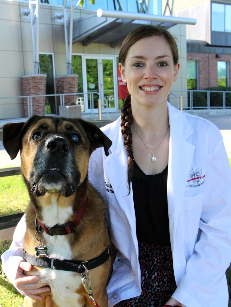 Caitlin Grant holding her dog Pilot in front of the OVC main building