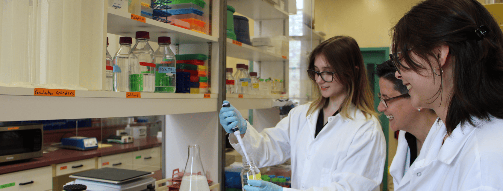 students wearing white coats in a lab 