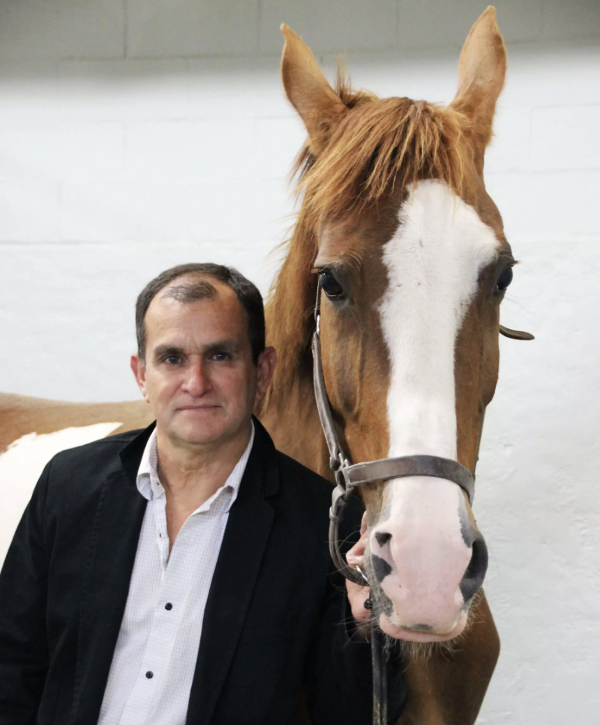 Luis G. Arroyo stands closely beside a tall horse